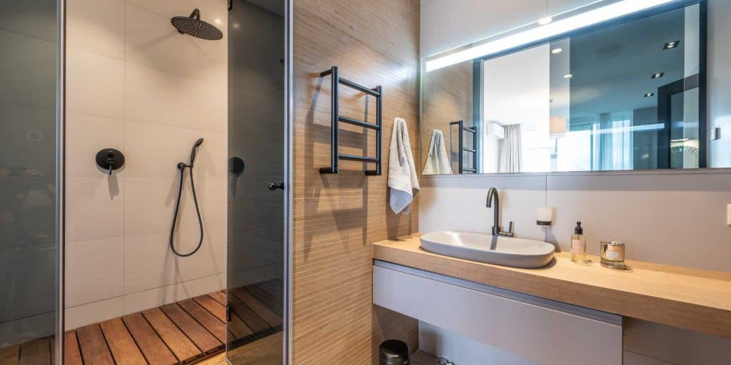 Contemporary bathroom featuring wooden cabinets and a stylish glass enclosure, crafted by Nativi Construction in Ventura County.